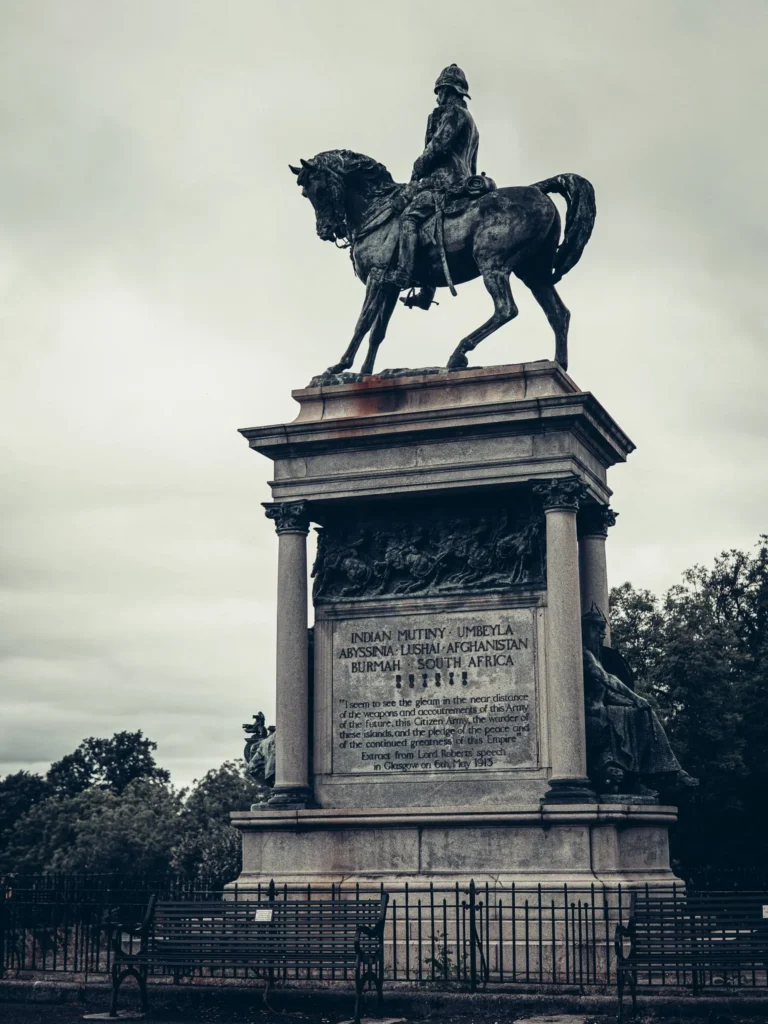 Bronze equestrian statue on a high stone pedestal, in a park in Glasgow.
