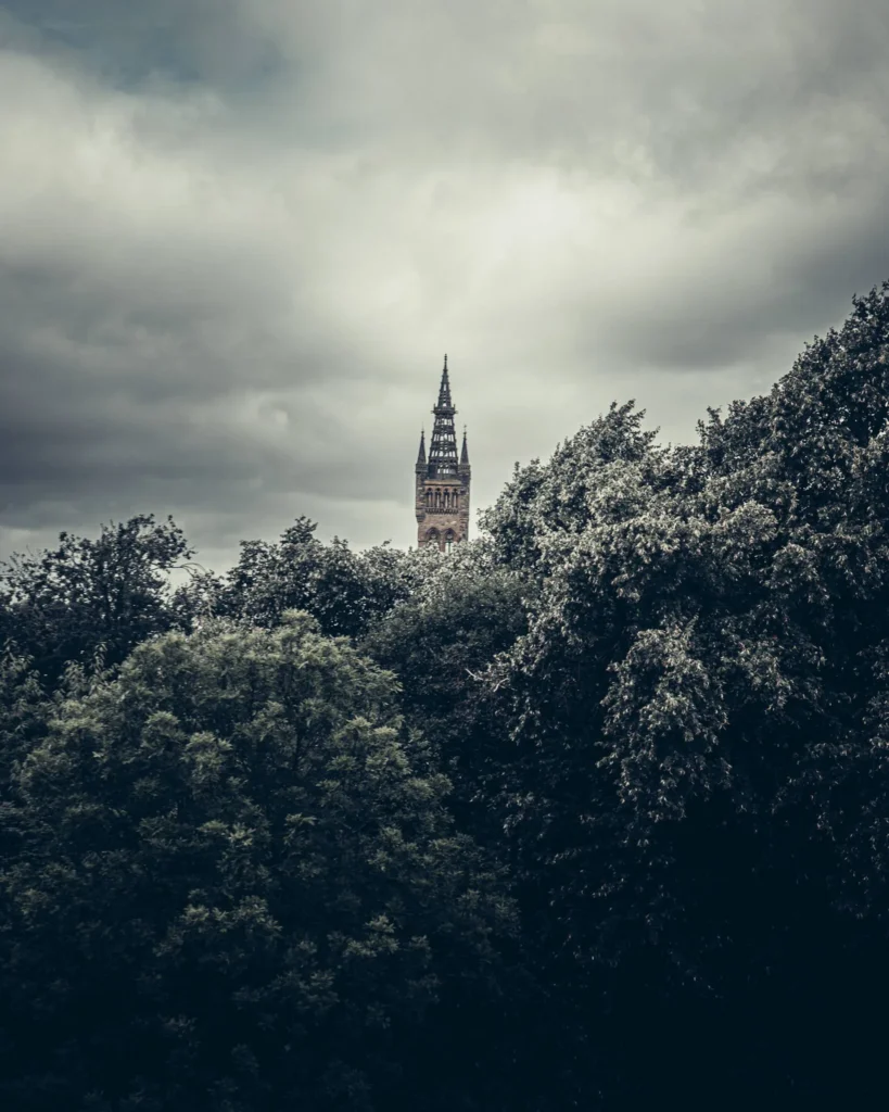 Gothic tower of a Victorian building rising above the trees in Glasgow. Seen from Kelvingrove Park, the university tower is easily mistaken for a church steeple.