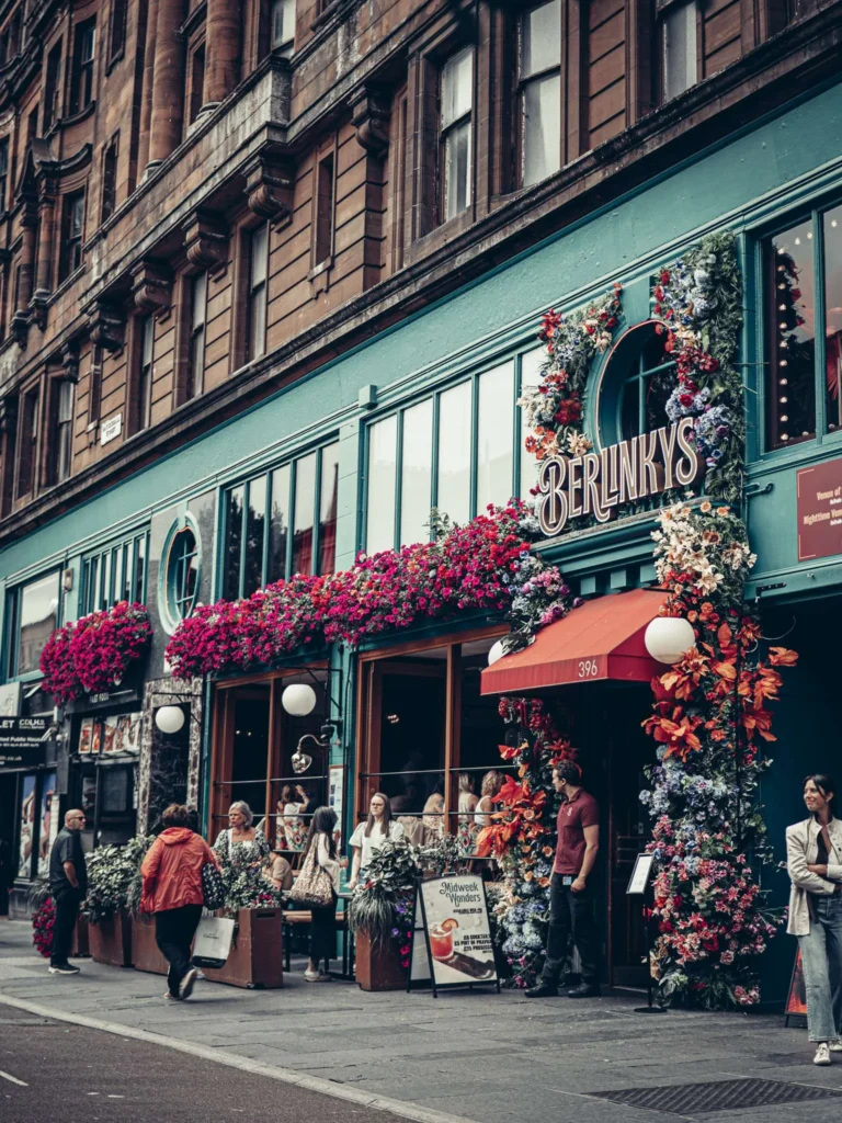 The BerlinKys café and its flowered facade, under a Victorian blond sandstone building in Glasgow.