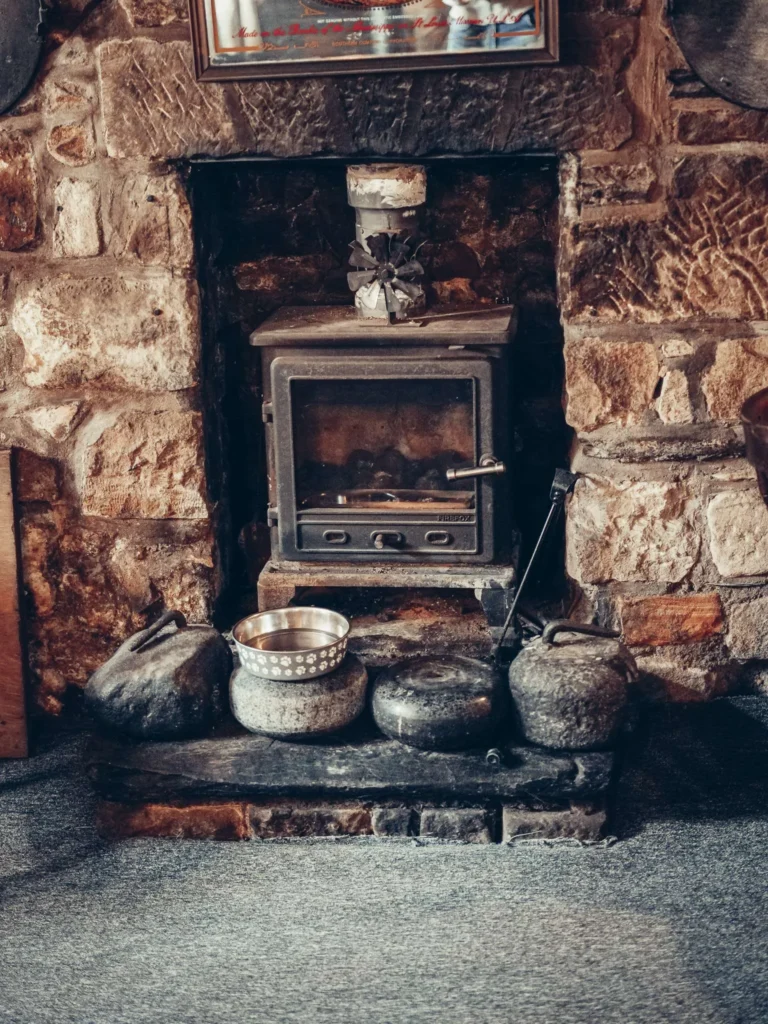 Stone fireplace and stove of the Settle Inn, in Stirling: with the dim light of the room, it gives the pub its cozy refuge look.