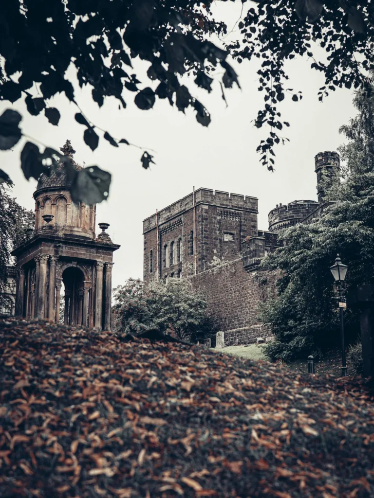 Historic stone building of the old town of Stirling, surrounded by greenery, old lamppost with glass lantern in the foreground.
