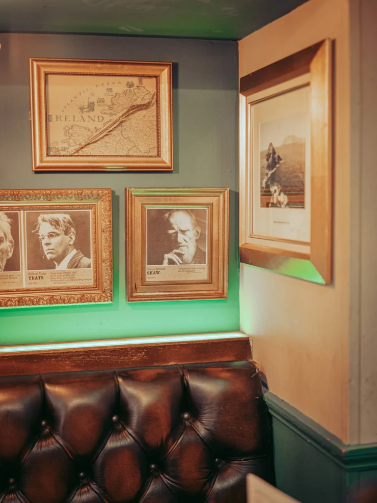 Corner of a pub in Stirling: dark leather bench and gold frames on the wall, including an old map and portraits of writers.