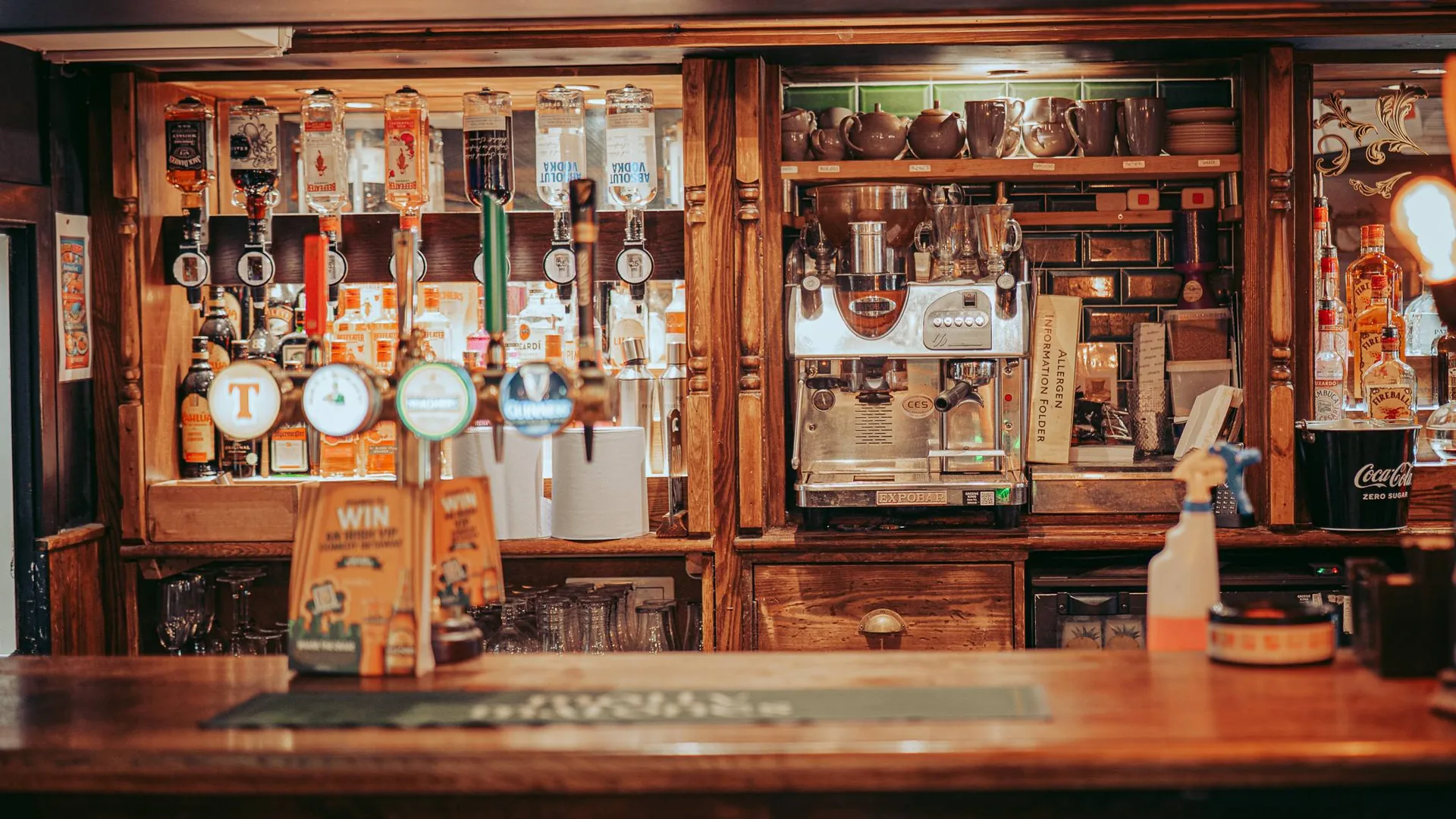 Wooden counter of a traditional pub in Stirling, beer taps and bottles behind the bar.