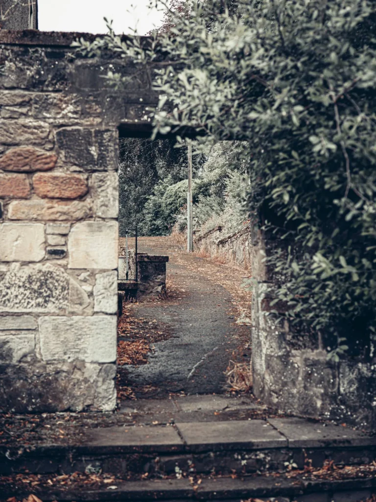 Stone entrance opening onto a winding path lined with mossy walls, in the old town of Stirling.