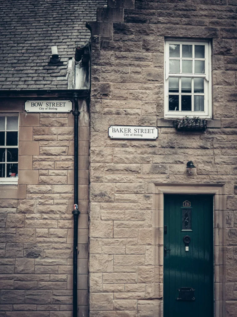 Stone facade of the old town of Stirling, at the corner of Bow Street and Baker Street, green door and small pane window.