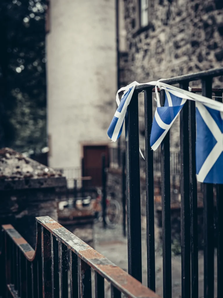 Banners in the colors of Scotland hanging from a wrought iron grid in front of an old building in Stirling.