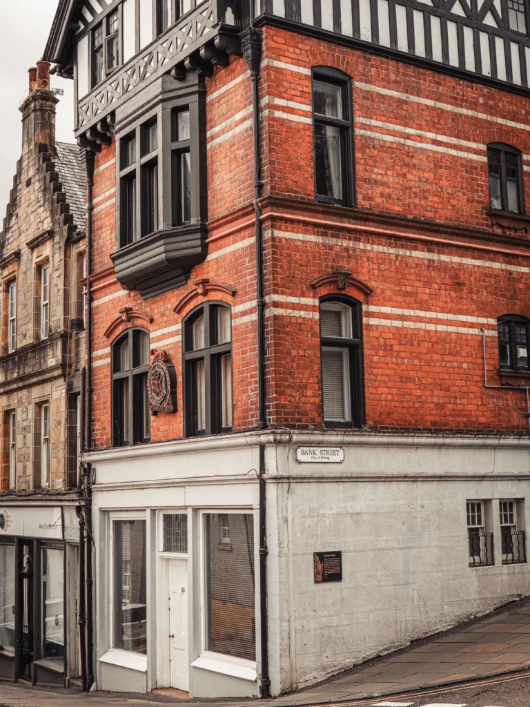 Large red brick and stone building at the corner of a sloping street in the old town of Stirling.