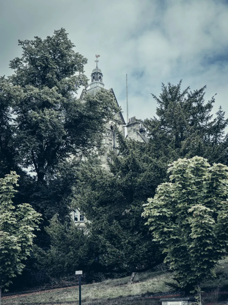 Large stone building partially hidden by trees, on the hill leading up to Stirling Castle.
