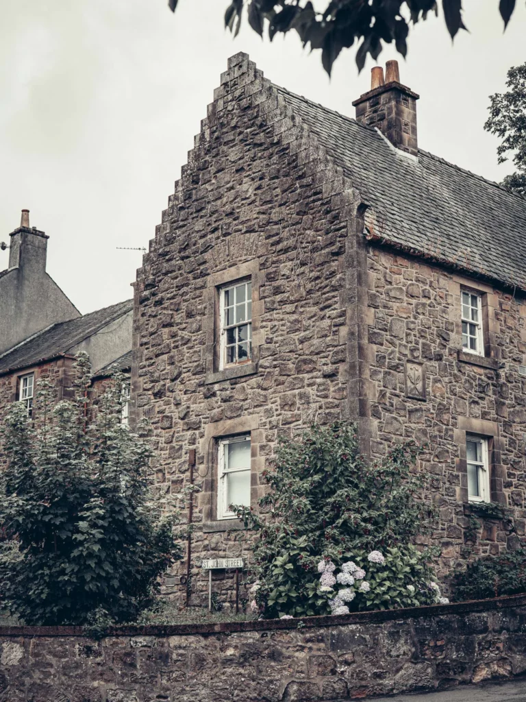 Stone-built house on St John Street in Stirling, stone wall and blooming hydrangeas in front of the facade.