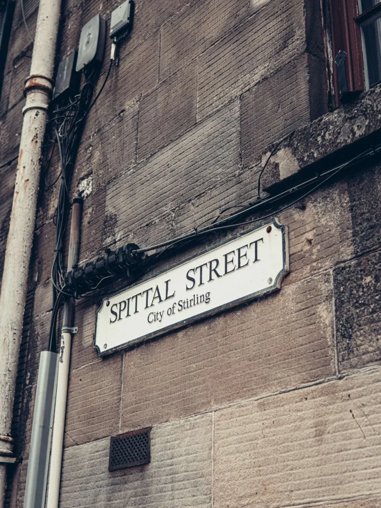 Spittal Street street sign on a stone wall in Stirling: this is the street of the Christmas shop Tinsel & Tartan, at the beginning of the climb to the castle.