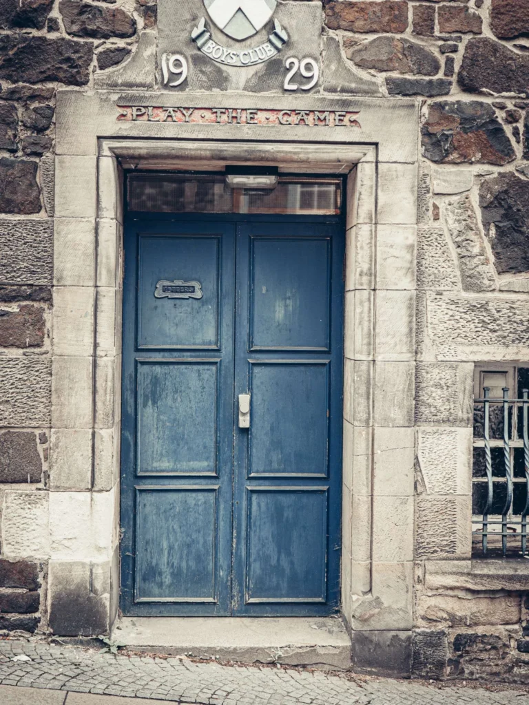 Blue door with the inscription "PLAY THE GAME" and the date 1929, in Stirling.