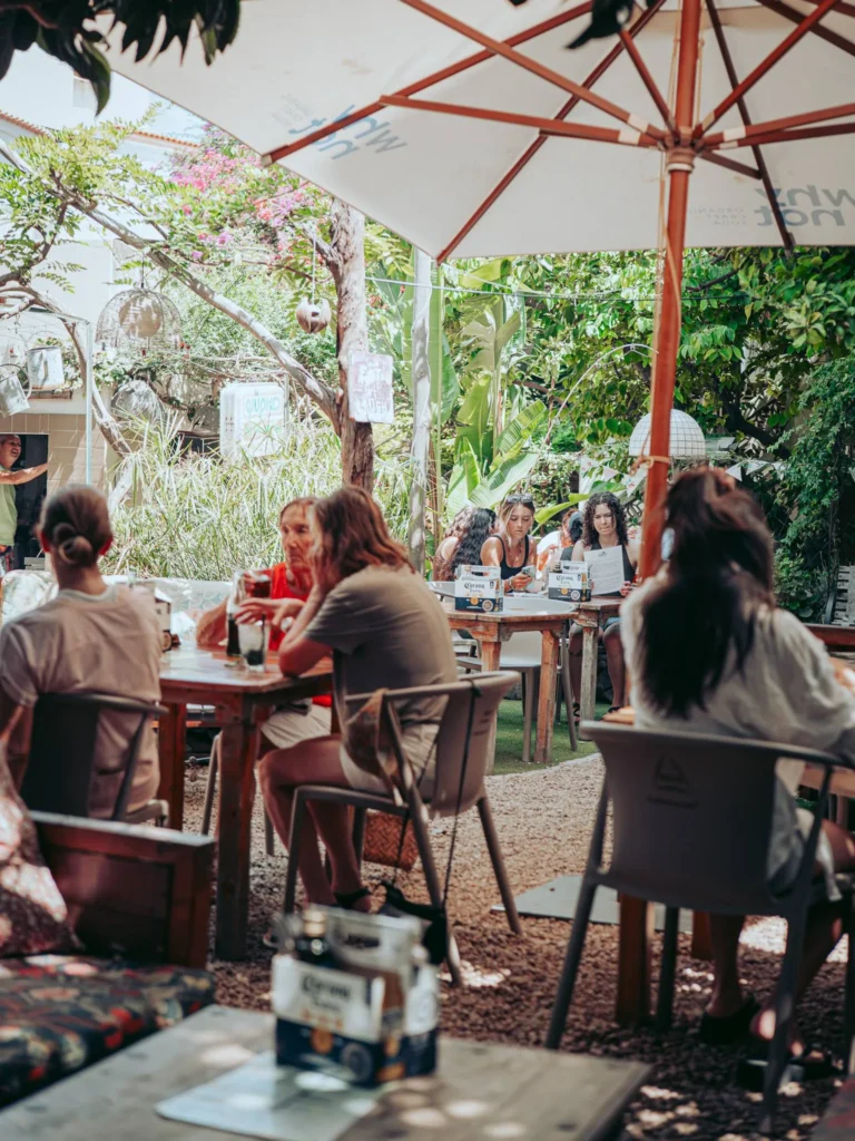 The garden of the restaurant The Garden Bar and Grill in Lagos, Algarve, with its occupied tables under large umbrellas and its dense vegetation.