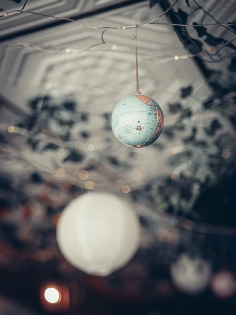 Suspended globe decoration under the ceiling of The Geographer in Fort William, dimly lit atmosphere with fairy lights.