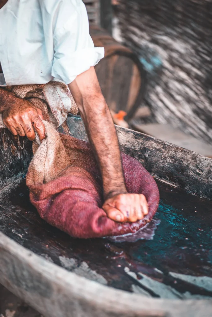 A man presses dyed fabric in a wooden basin, illustrating a craft demonstration at the medieval festival of Castro Marim in the Algarve.