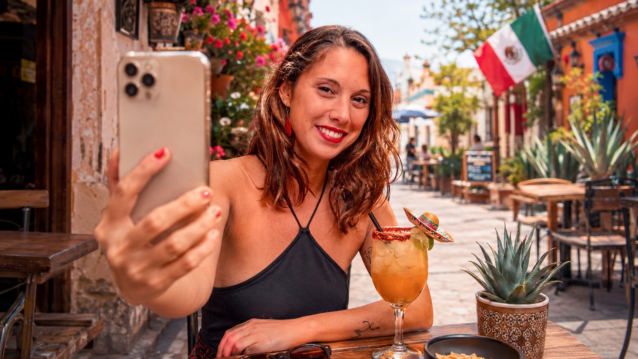 Viaggiatrice sorridente che si fa un selfie in una via colorata del Messico.