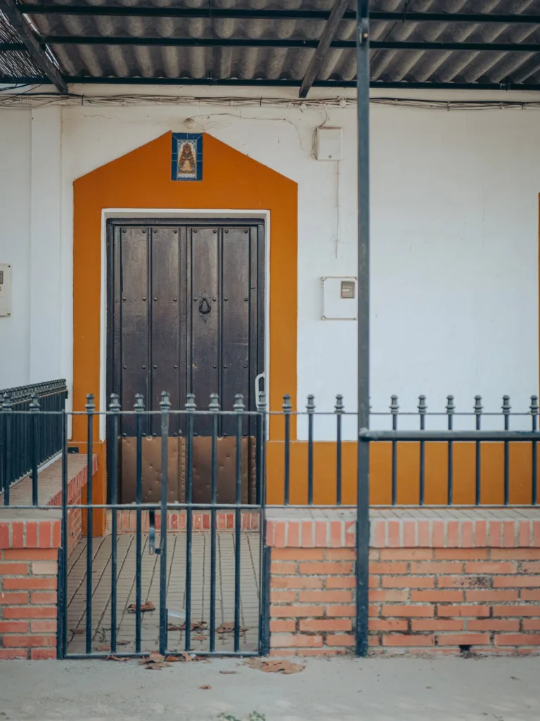 Porta di legno scuro, cornice ocra e ceramica religiosa sopra un ingresso a El Rocío