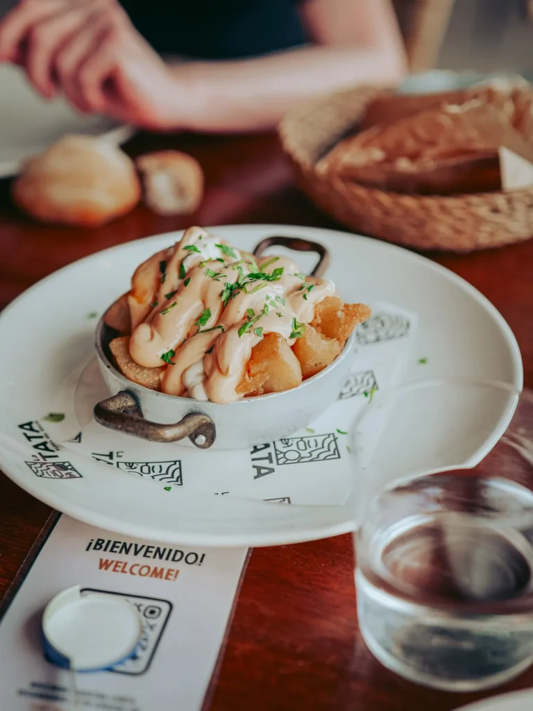Mezza porzione di patatas bravas ricoperte di salsa da La Tata a El Rocío