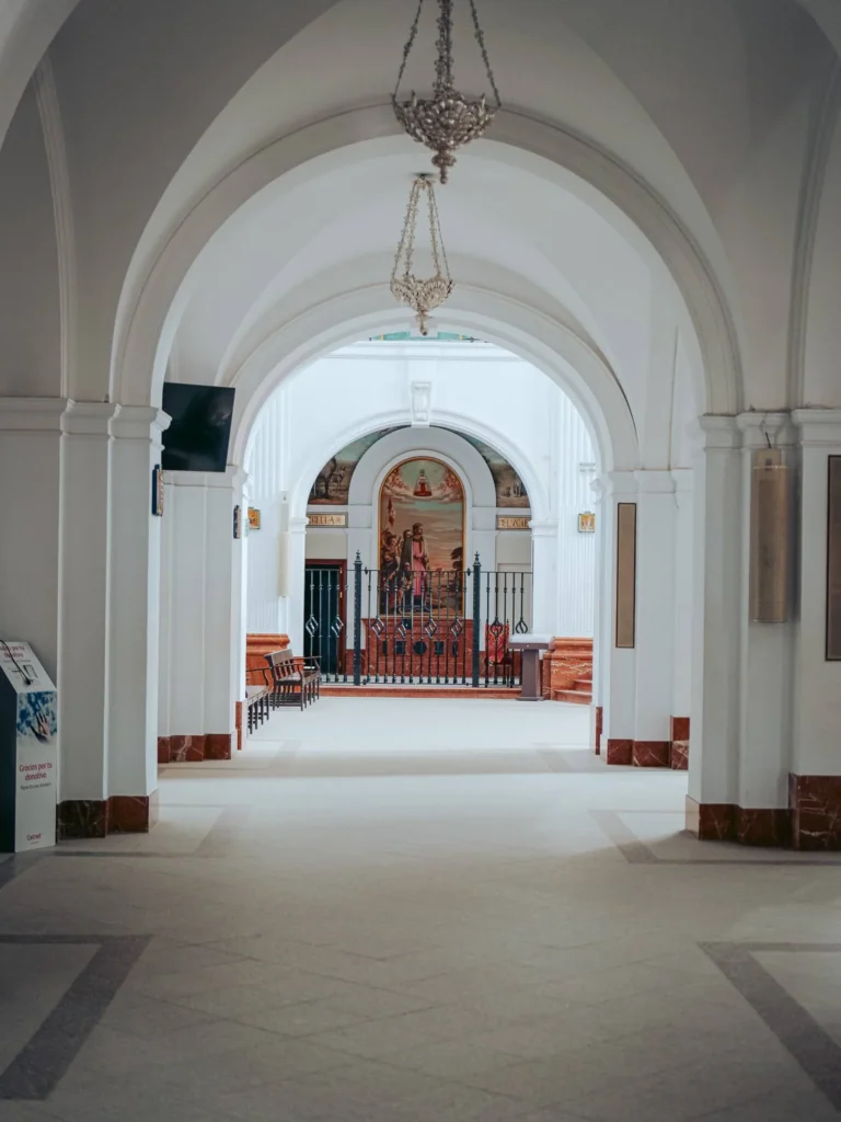 Archi bianchi e lampade sospese in una navata laterale del santuario del Rocío