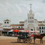 Carrozza e santuario bianco accanto alla piazza di sabbia di El Rocío